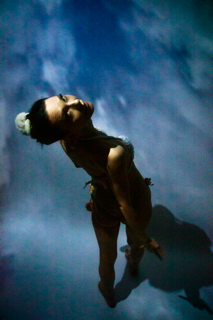 A women in a bikini standing in the sky looking up at the viewer.